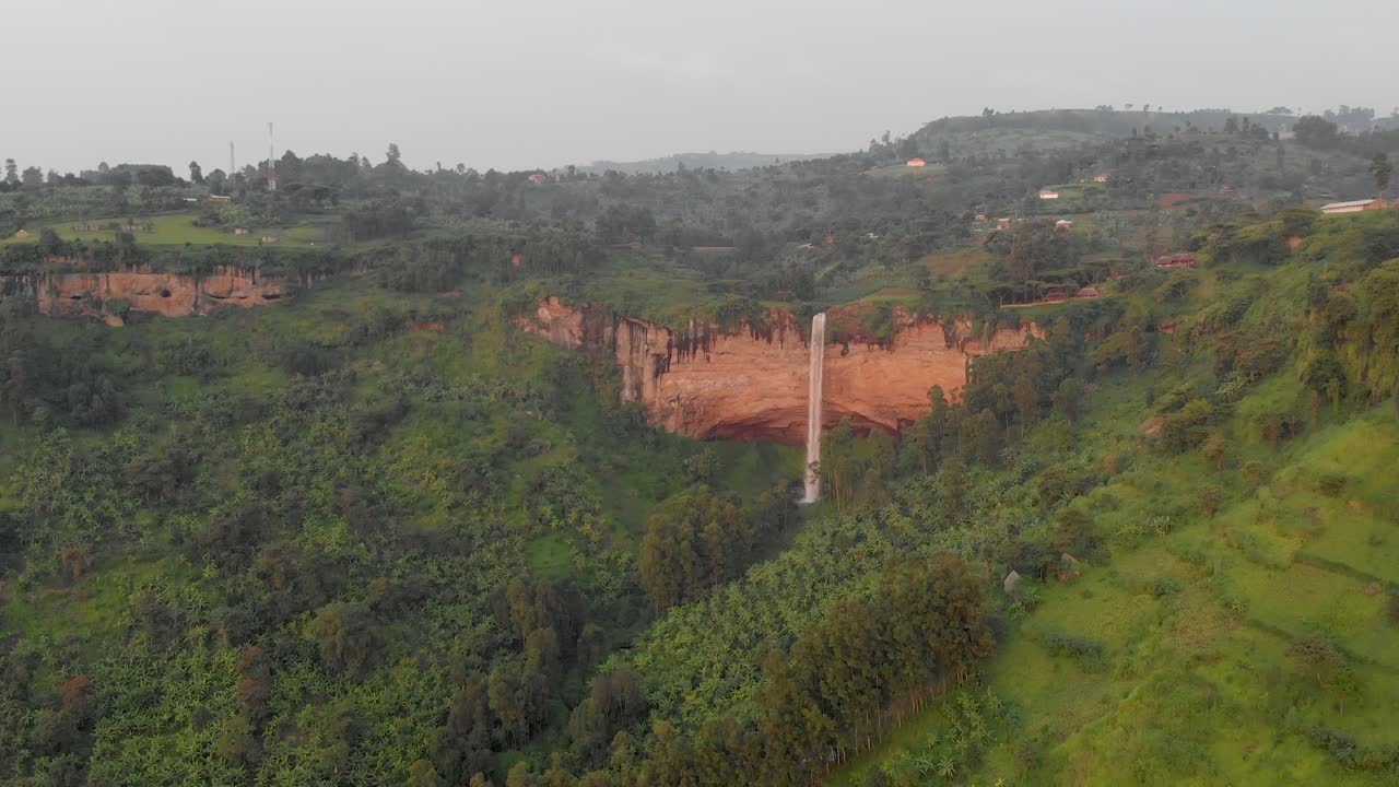 una toma aérea panorámica hacia atrás de las cataratas sipi que caen sobre el borde de un acantilado en el áfrica rural