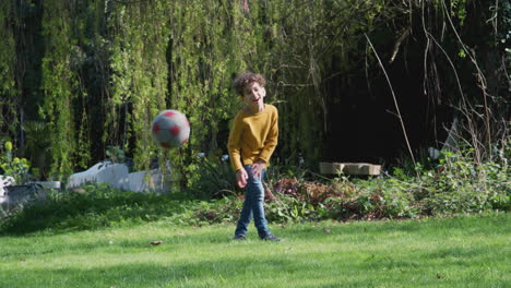 niño pateando una pelota de fútbol en el jardín en casa