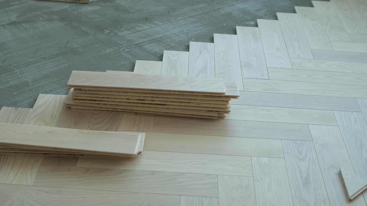 Worker installing wooden flooring with hammer and tapping block