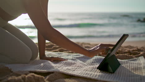 girl putting tablet yoga mat lying sand beach close up. woman preparing training