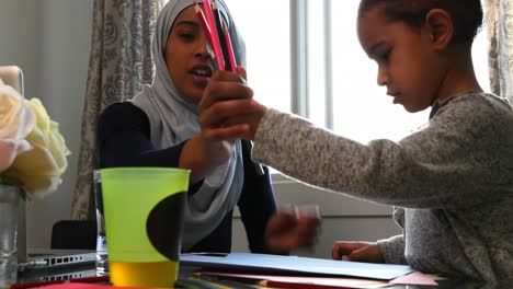 young mother choosing color pencils with her daughter table at home 4k