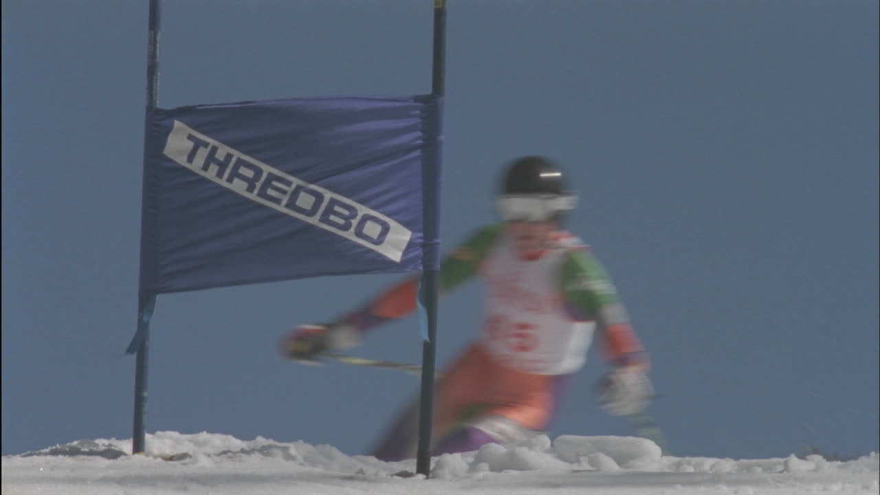 스키어가 슬라롬 코스를 통해 언덕 아래로 빠르게 이동합니다.