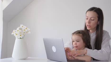 a workathome mom on maternity leave mother works at the computer with her child a workathome mom on maternity leave mother works at the computer with her child the child interferes with the mothers work at the computer