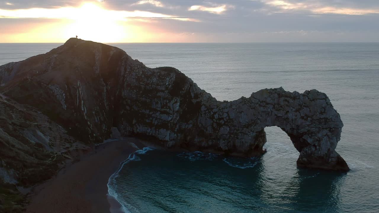 Durdle Door at sunrise with a man on the cliff