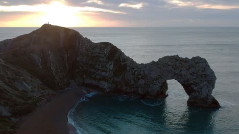 durdle door at sunrise with a man on the cliff