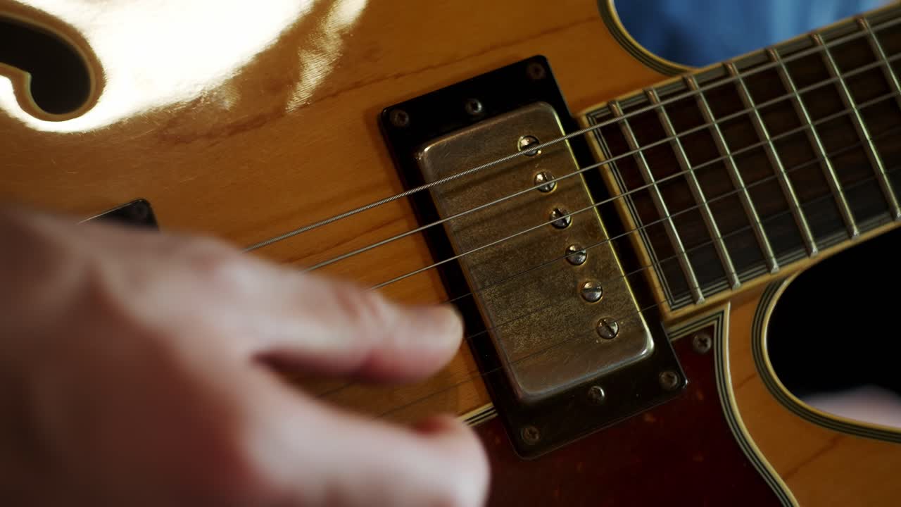 Close up view of a Man's beautiful hand playing a solo an expensive electric guitar in a home studio.