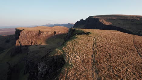 Fast-drone-dolley-tilt-shot-over-a-man-looking-at-the-landslide-in-Quiraing-in-Scotland-during-a-setting-sun