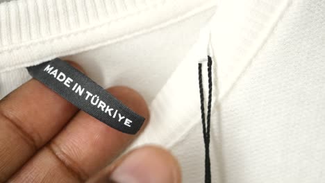 close-up of a clothing tag that says "made in turkey" on a white t-shirt.