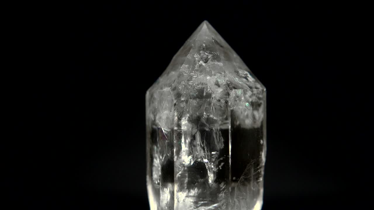 rotación sin problemas de un mineral (cristal de cuarzo) frente a un fondo negro