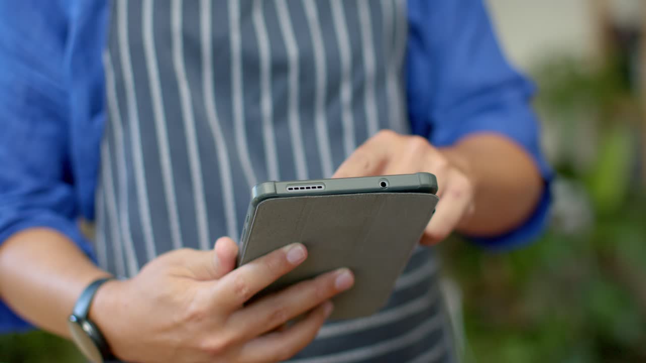 African American nonbinary holding tablet, finger starting tapping, swiping at cafe checking orders