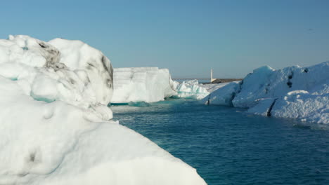 Schöne-Drohnenansicht-Kalte-Landschaft-Der-Breidamerkurjokull-gletscherlagune-In-Island-Mit-Schwimmenden-Eisbergen.-Luftaufnahme-Des-Jokulsarlon-Sees-Mit-Metallbrücke-Im-Hintergrund