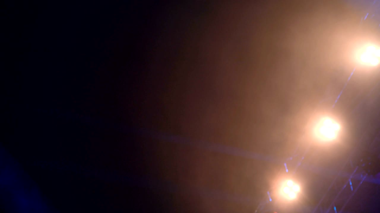 los rayos de los reflectores de 4k atraviesan los alrededores oscuros llenos de humo del escenario durante el concierto