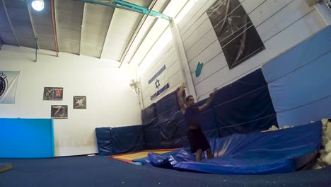 a slow motion still shot of a guy doing flips from the trampoline landing and winning having fun and working out in 60fps