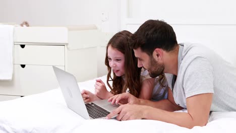 padre y hija felices usando computadora portátil