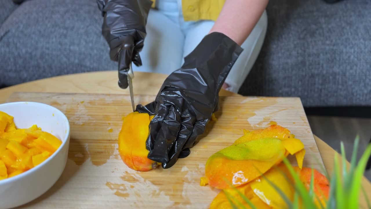 Close-up 4K footage of mango slicing with black gloves. Ideal for food prep, safety, hygiene, culinary tutorials, nutrition, and summer fruit visuals. Shot in high detail and color.