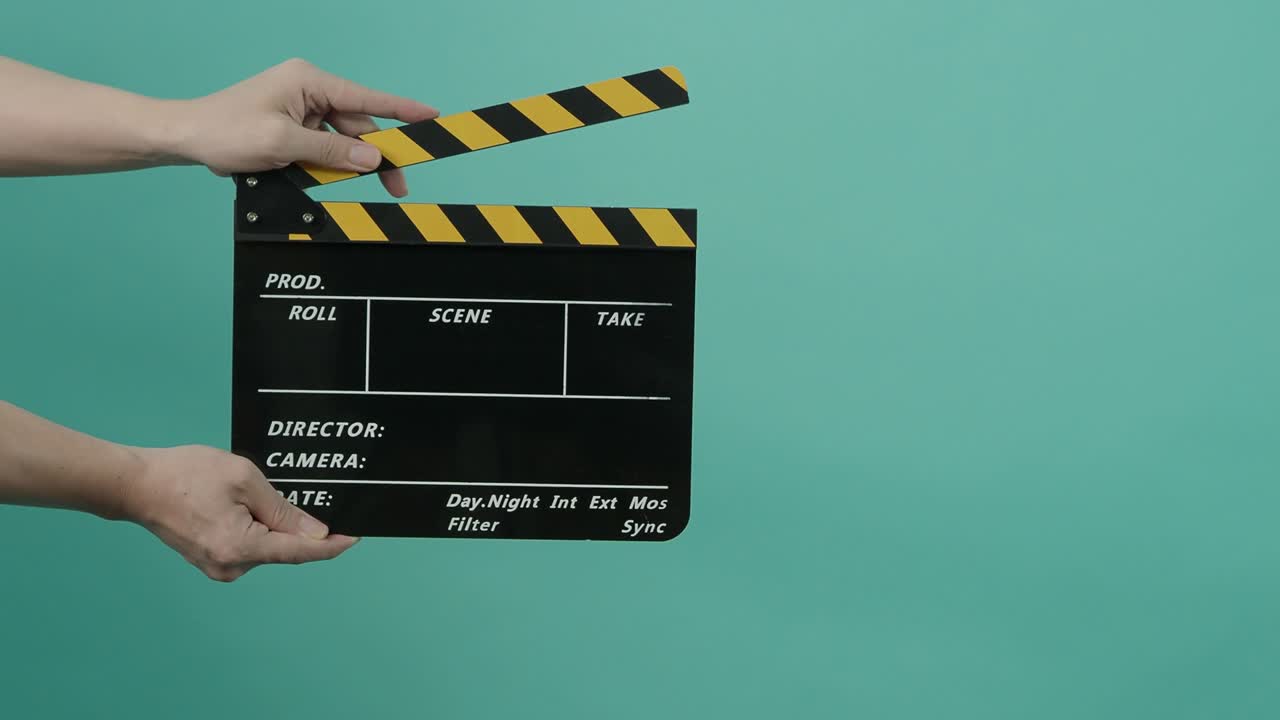 pizarra de película o clapperboard de película con fondo de pantalla verde azul. el hombre de la tripulación de la película sostiene y golpea la pizara de película en el marco. aplaudiendo la pizarra de la película. producción de video fondo clave de croma. producción de vídeo.