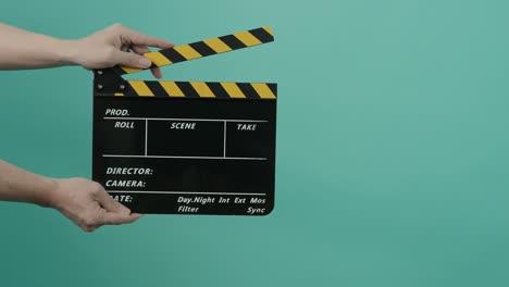 film slate or movie clapperboard with blue green screen background. film crew man hold and hit film slate in the frame. clapping film slate. video production chroma key background. video production.