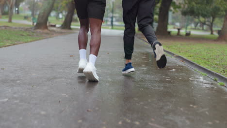 two men running in a park on a rainy day