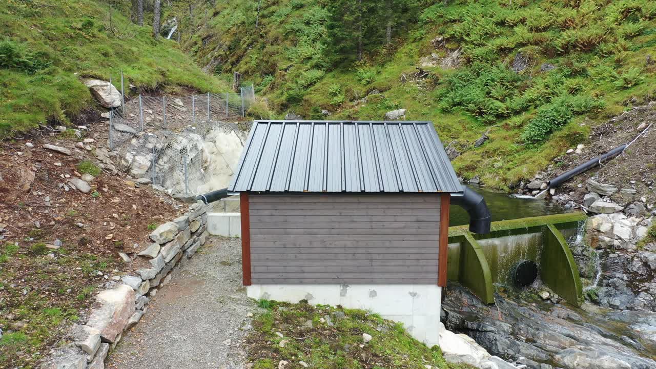 casa de control de válvulas y pequeña presa de entrada para la central hidroeléctrica del río markaani en vaksdal noruega - bajo nivel de agua en las montañas durante el verano