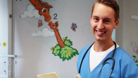 Smiling-doctor-holding-medical-report-in-hospital
