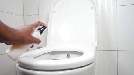 a person cleaning a toilet with a spray bottle