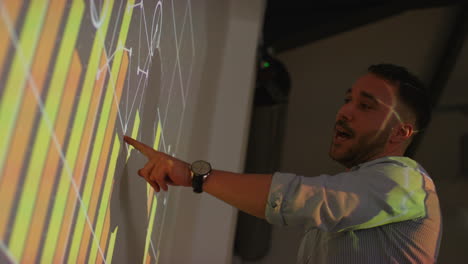 close up of male teacher giving maths or science lesson in school standing at the front of class with projection of graph