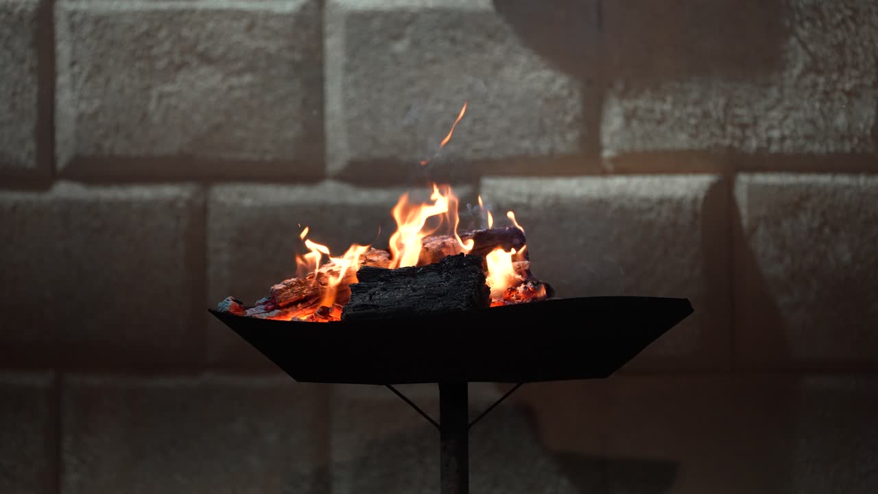 Antiguo brasero con leños ardiendo por la noche, creando humo, tiempo frío y calidez