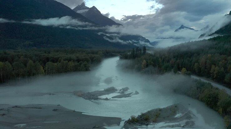 Strato di nebbia sopra un fiume che scorre attraverso una catena montuosa nella Columbia Britannica, vista aerea.