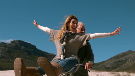 Carefree-mature-couple-going-for-bike-ride-on-the-beach