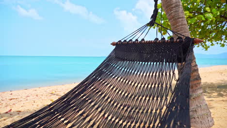 empty hammock on deserted sandy tropical beach, close up of swinging bed by blue sea on exotic travel destination, full frame