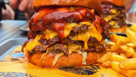 four-layer hamburger dripping with cheese and sauce with french fries - close up