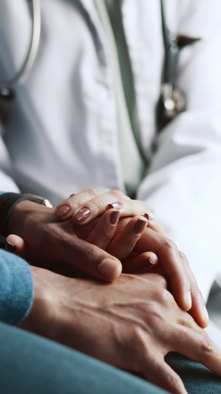 Medico che conforta il paziente tenendogli le mani in un contesto medico