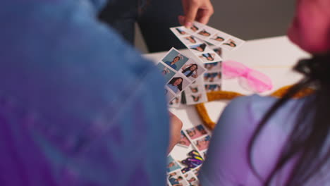 close up of a group of friends having fun looking at prints from photo booth with props 13