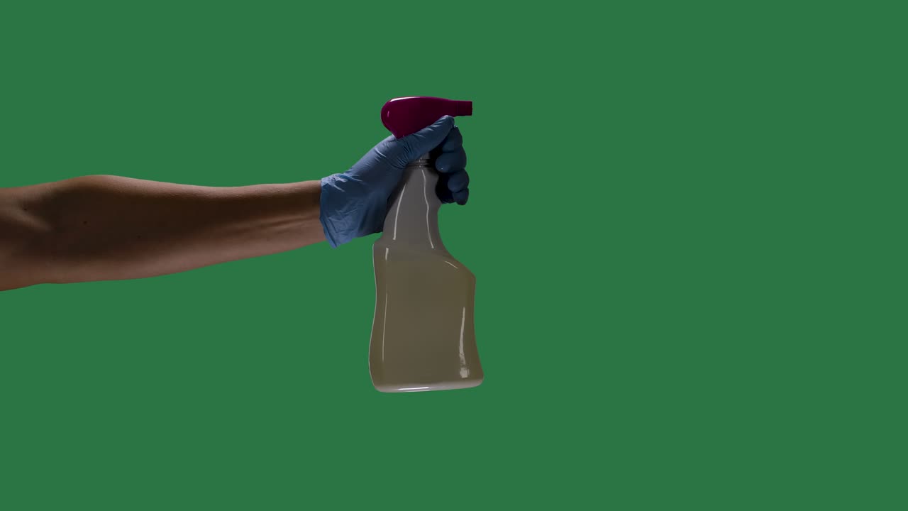 silueta de una mano de un hombre con guantes de protección azules sostiene una botella de spray y pulveriza un agente alcohólico desinfectante para desinfectar el virus de la corona covid 2019. pantalla verde, llave de croma. cámara lenta. primer plano