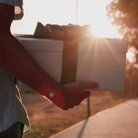 a man carries a beautifully packed box with a gift walks down the street in the sun 1