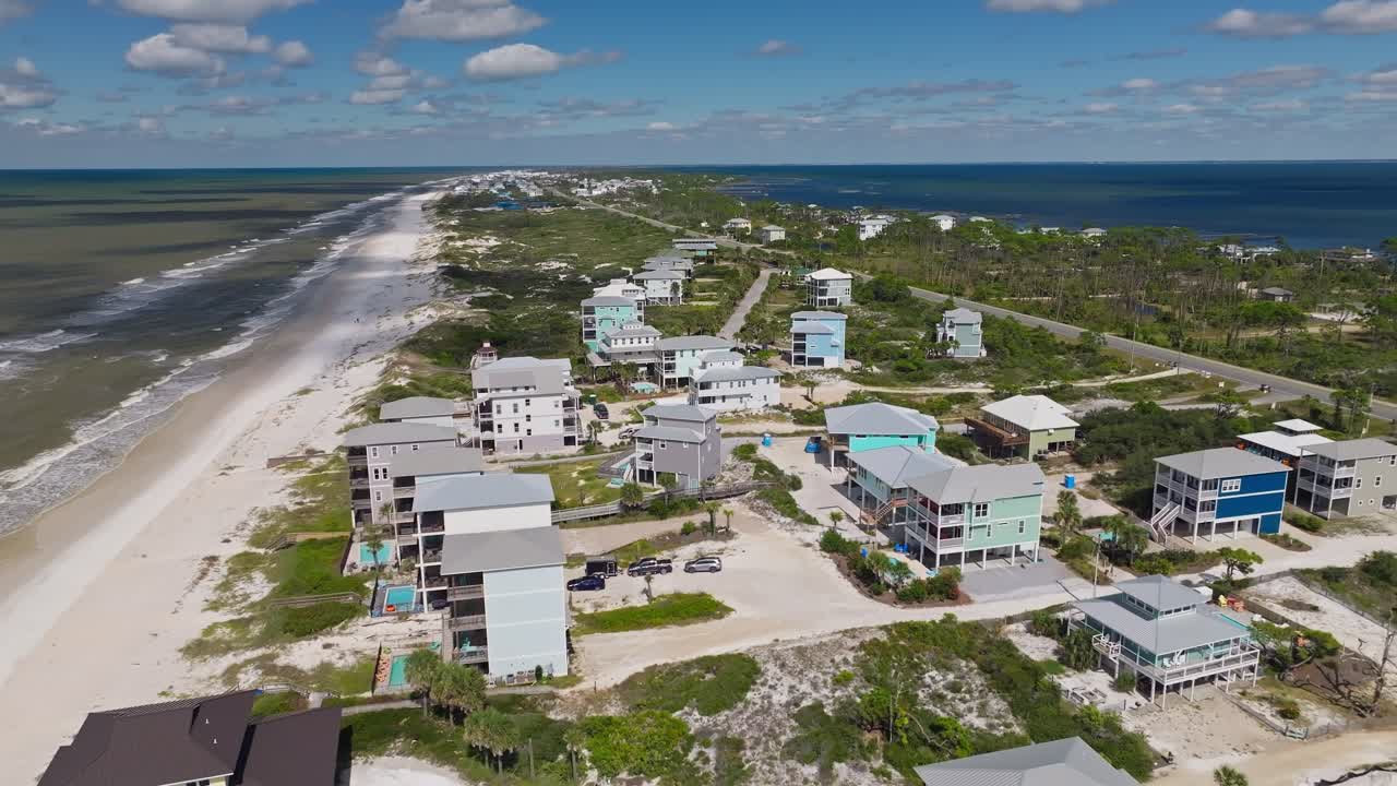 clip aéreo de coloridos condominios y vegetación exuberante contra playas de arena en cabo san blas, florida