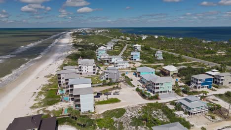 aerial clip of colorful condos and lush vegetation against sandy beaches at cape san blas, florida