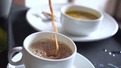 pouring hot brown coffee into a cup for breakfast at the hotel - close up