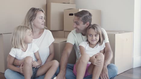 couple of parents and two daughters sitting on floor