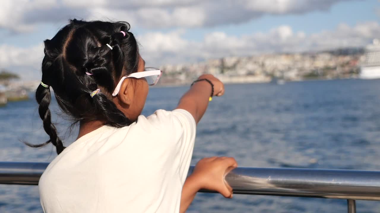 Girl pointing at a cityscape on the sea