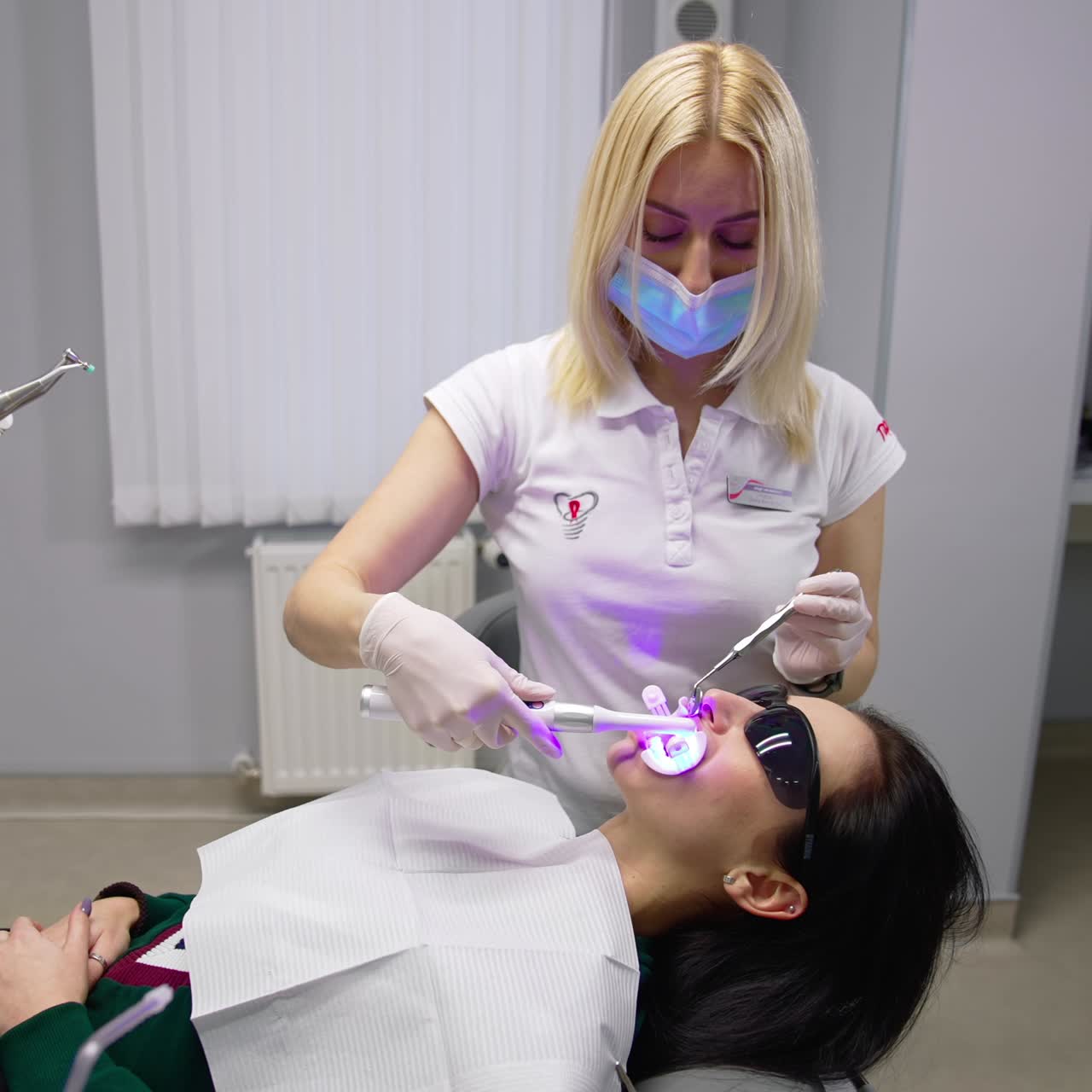 Klinikte diş tedavisi gören kadın. Diş kliniğinde hasta ile güler yüzlü kadın diş hekiminin portresi.