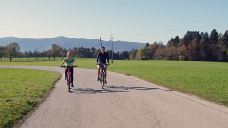 Cyclist-couple-pedaling-on-a-countryside-road,-giving-a-high-five,-front-view