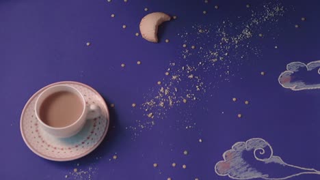 alguien toma de una mesa hecha en forma de un cielo nocturno una taza de café en primer plano