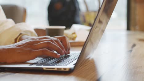 Persona-Ocupada-Escribiendo-En-El-Teclado-De-La-Computadora-En-Una-Mesa-De-Café-En-Una-Cafetería-Por-La-Mañana