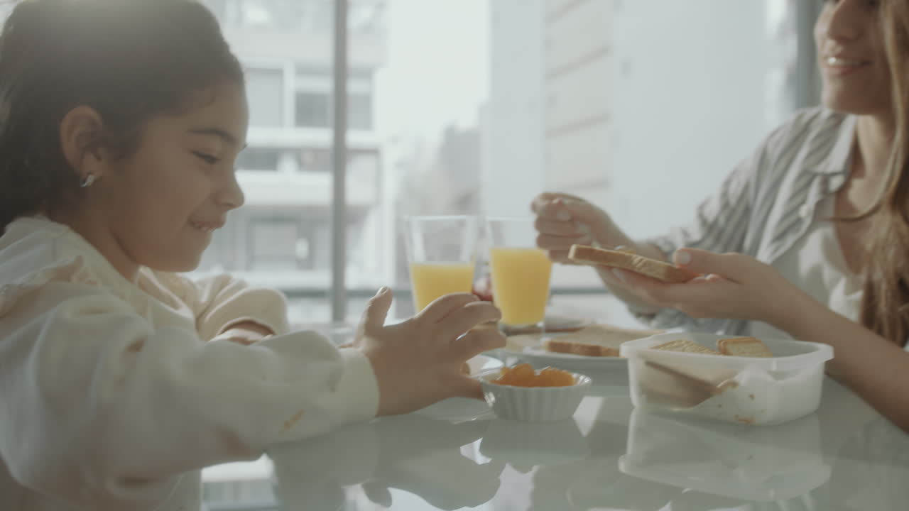 Careful Mother Making Toast with Jam for Little Daughter on Breakfast