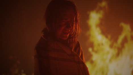 a crying child wrapped in a blanket by firelight