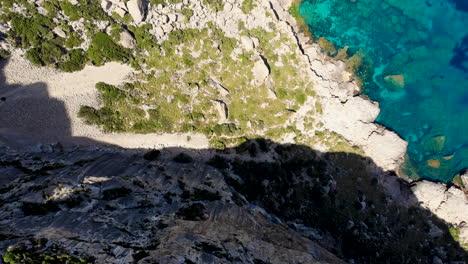 Antena-De-Arriba-Hacia-Abajo-Sobre-Un-Acantilado-Junto-Al-Azul-Brillante-Del-Mar-Balear,-Mallorca