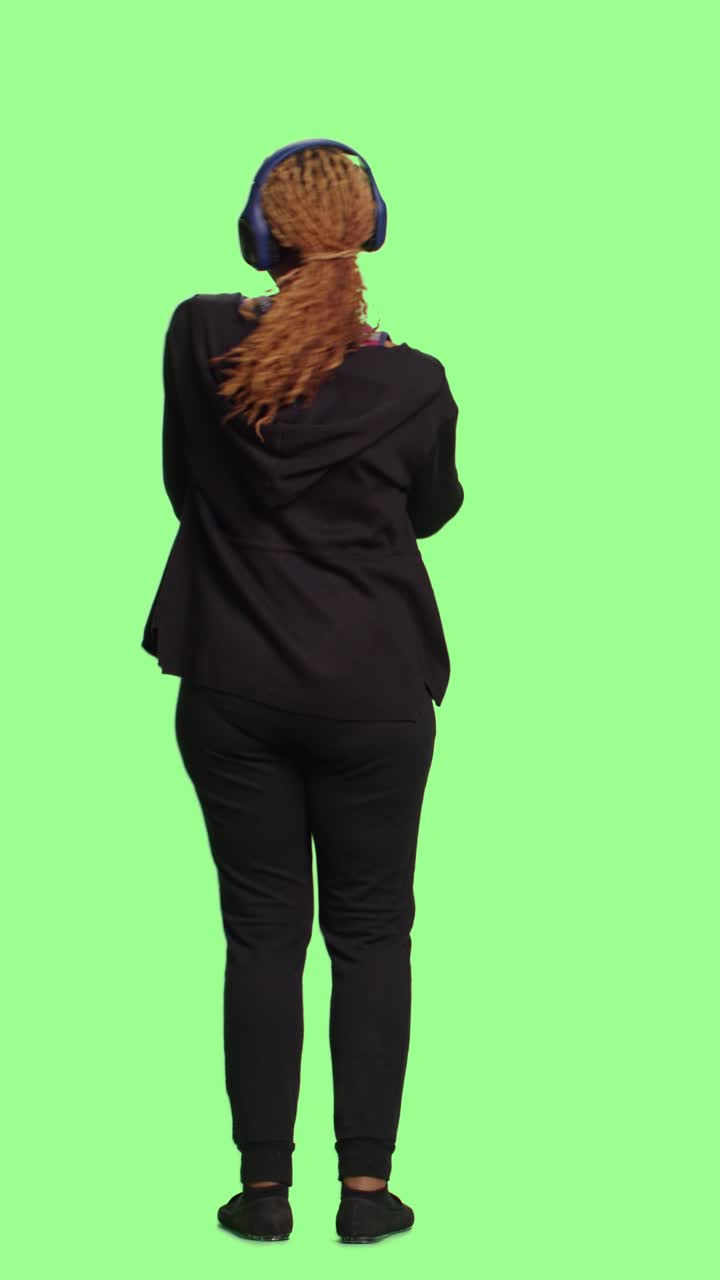 Video verticale: ragazza moderna e allegra che ascolta musica con cuffie audio