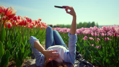 Mujer-Joven-Relajada-Balanceando-Las-Piernas-En-El-Fondo-Del-Cielo-Azul-En-El-Campo-De-Tulipanes.