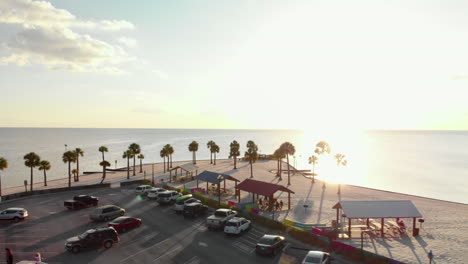 aerial low arc, immaculate white beach with sunrise over water